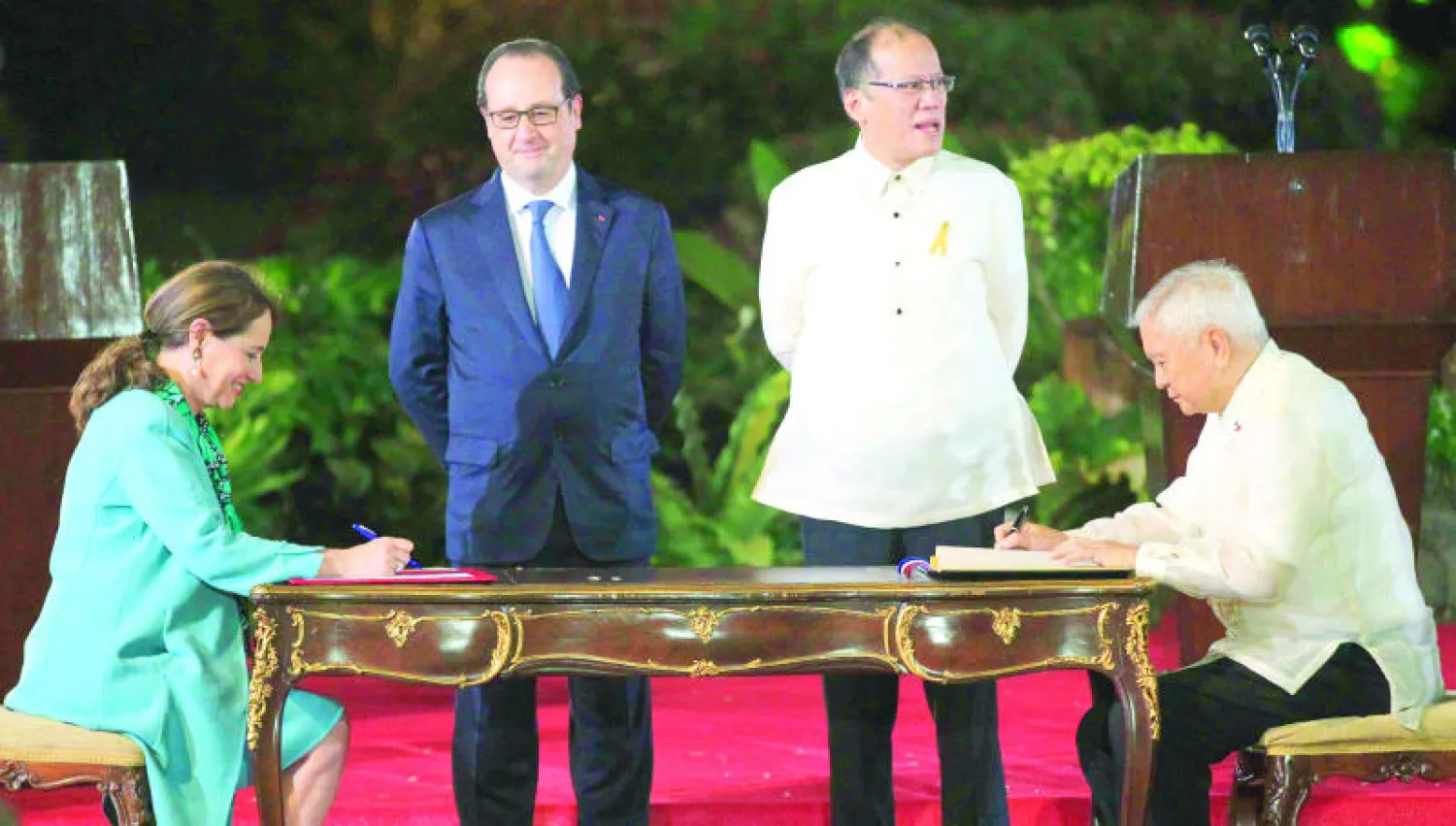 الرئيسان هولاند وأكينو يشرفان على إبرام اتفاق وقعه وزير الخارجية الفلبيني ألبيرتو دل روساريو ووزيرة البيئة الفرنسية سيغولين رويال في مانيلا أمس (رويترز)