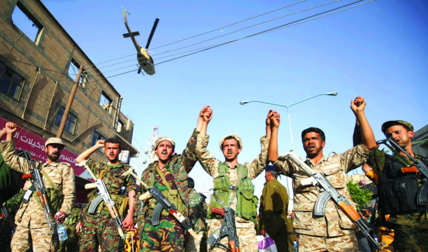 مقاتلون حوثيون بأزياء عسكرية، وتبدو طائرة هليكوبتر تحلق أثناء تجمعهم في صنعاء أمس (رويترز)