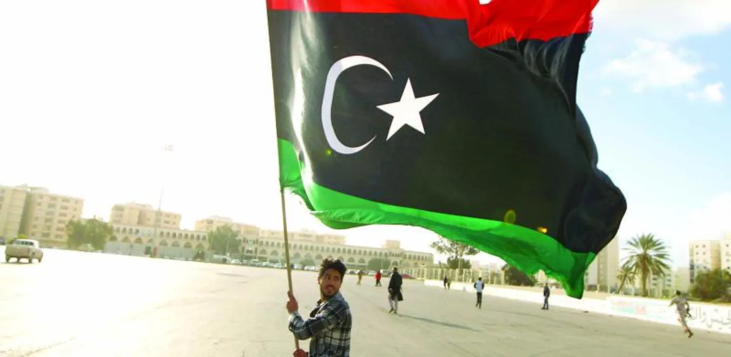 ليبي يلوح بعلم بلاده أمس على هامش مظاهرة في بنغازي تطالب باعتبار الجماعات الإسلامية «جماعات إرهابية» (أ.ف.ب)