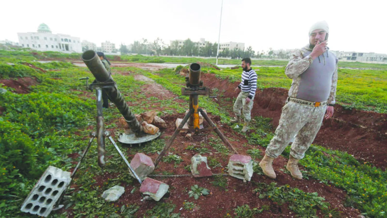 مقاتلون من لواء «أحفاد حمزة» يجهزون لإطلاق قذائف باتجاه القوات النظامية قرب مطار حلب (رويترز)