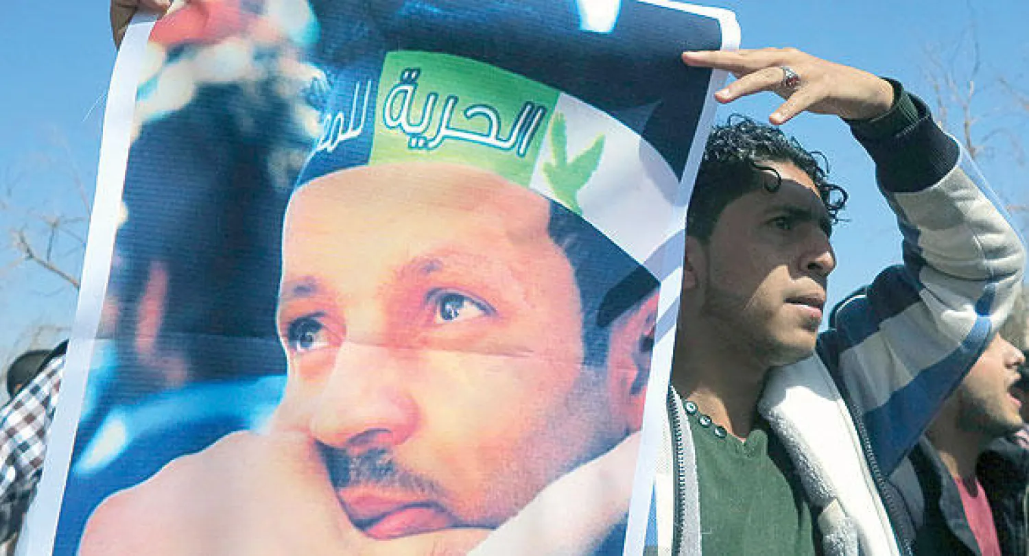 طالب بجامعة صنعاء يحمل صورة محمد الصبري وهو ناشط اعتقله الحوثيون  في احتجاجات طلابية ضد تنظيم الحوثي في صنعاء أمس (رويترز)