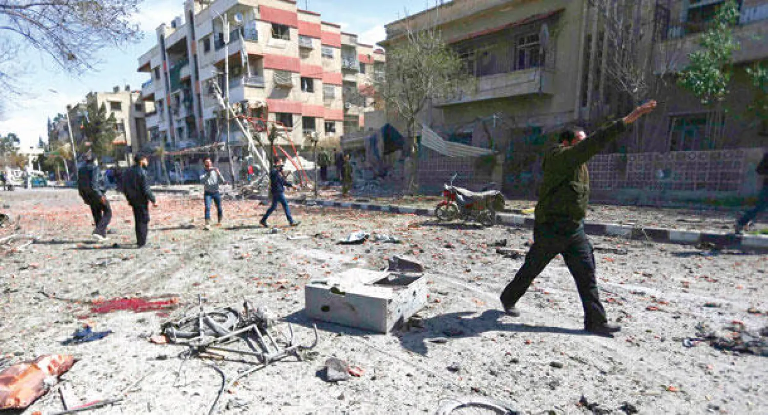 سوريون يتفقدون موقعا قصفته قوات النظام السوري في دوما بالغوطة الشرقية قرب العاصمة دمشق أمس (رويترز)