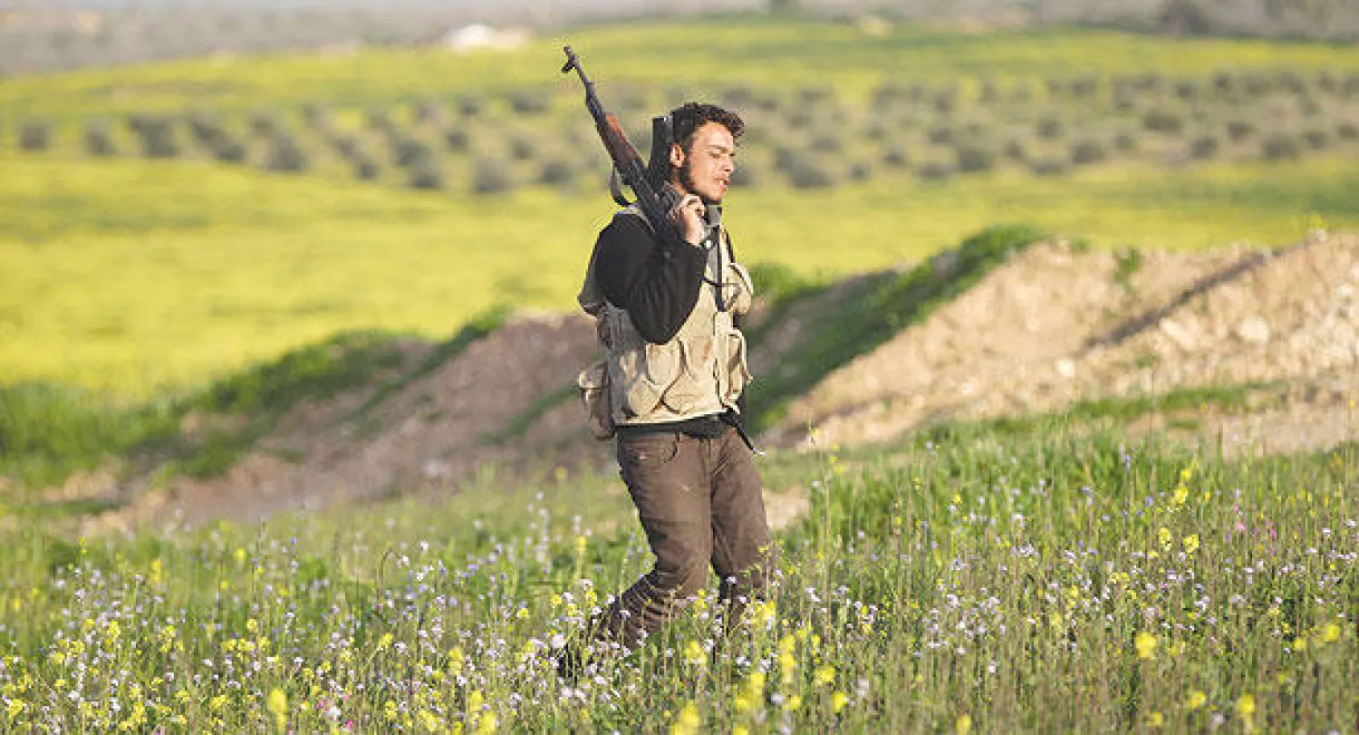 مقاتل من الجيش السوري الحر يعبر حقول بلدة مورك بريف حماه وسط سوريا أول من أمس (رويترز)