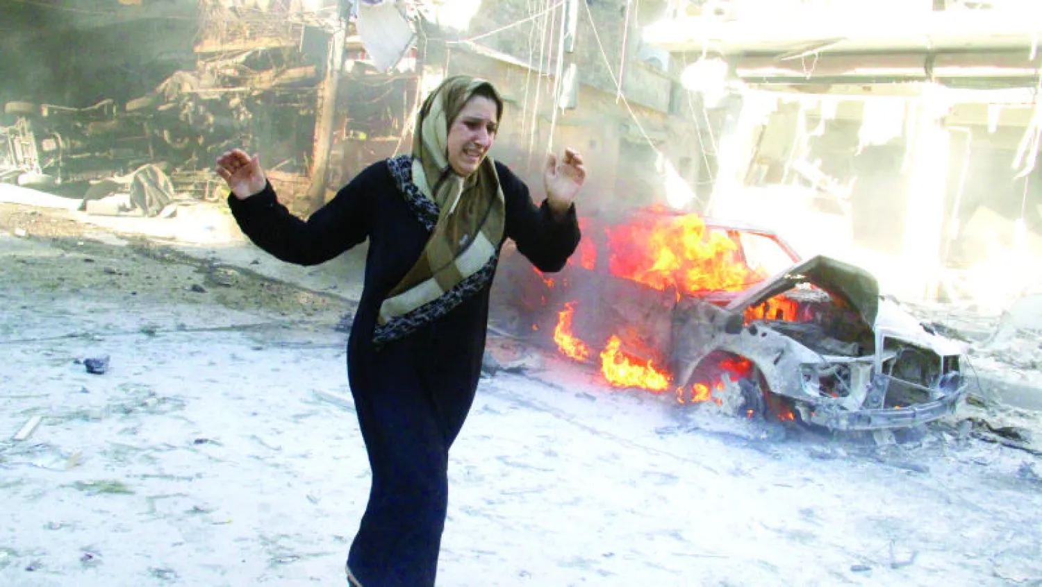 صورة لسورية تحاول تجاوز سيارة مشتعلة بفعل قصف قوات النظام لمنطقة في شمال حلب في مايو الماضي (أ.ف.ب)