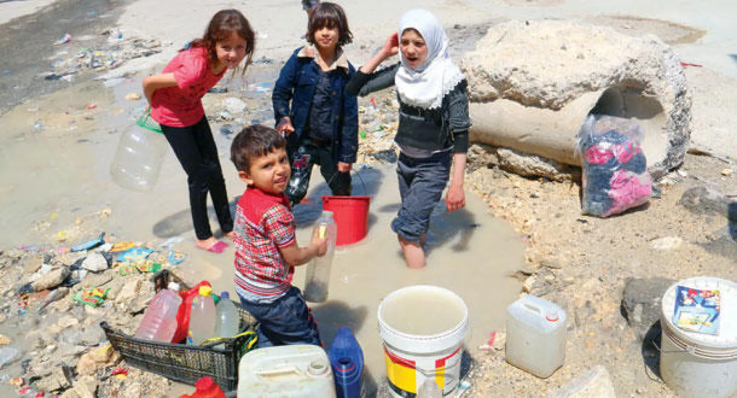 أطفال سوريون يعبئون صفائح ماء من مياه أمطار في مناطق تسيطر عليها المعارضة في حلب في مايو الماضي (غيتي)