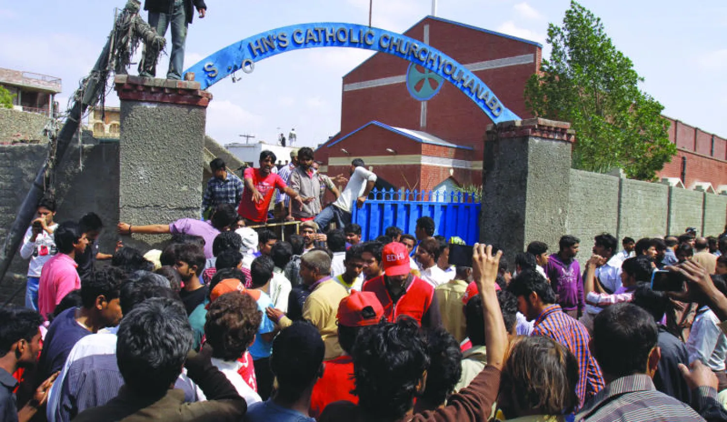 باكستانيون مسيحيون أمام إحدى كنيستين تعرضتا أمس لتفجيرين في مدينة لاهور (أ.ب)