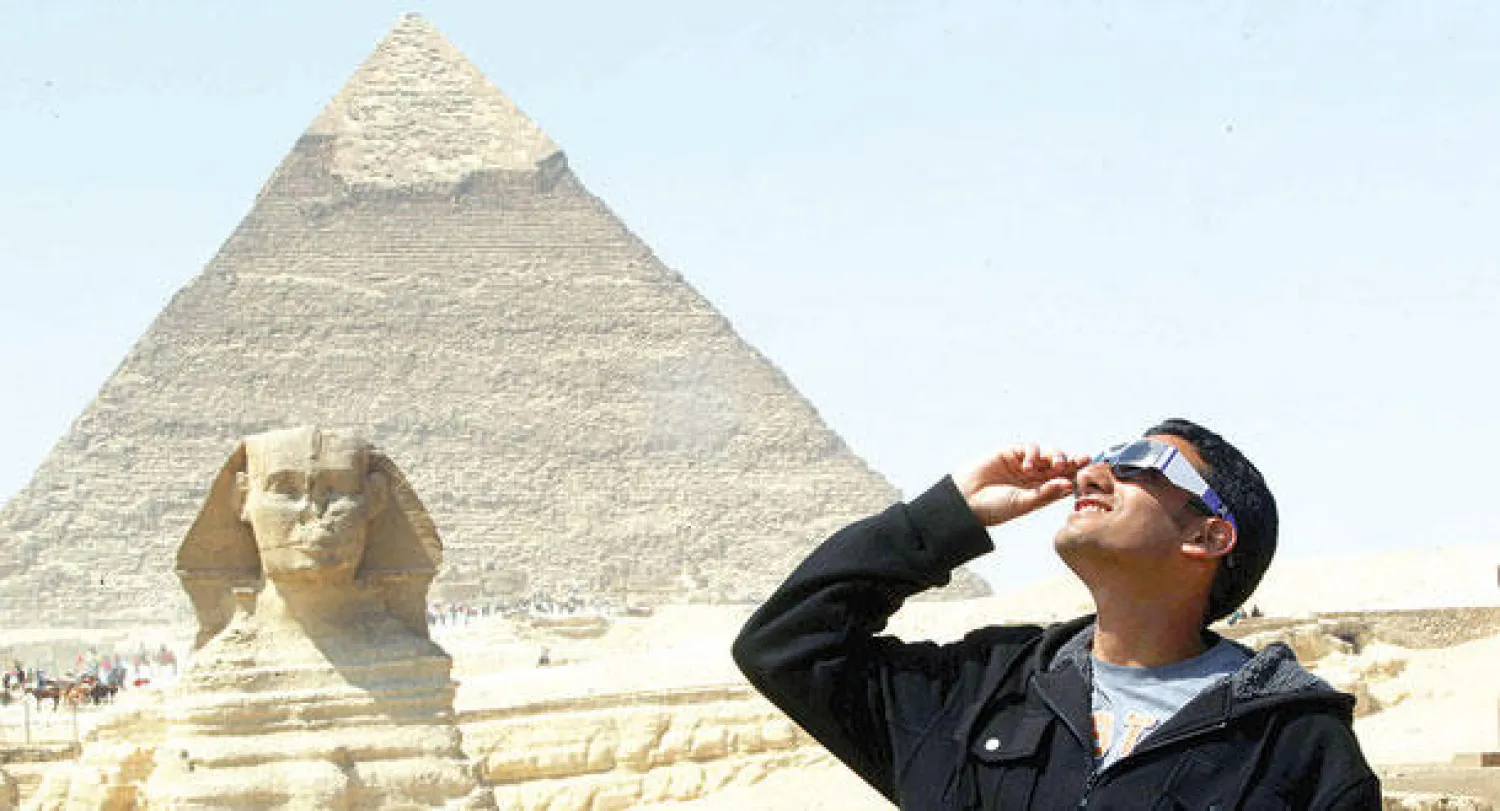 سياح ومواطنون مصريون عند الهرم الأكبر  في الجيزة لمشاهدة الكسوف الجزئي للشمس (إ.ب.أ)