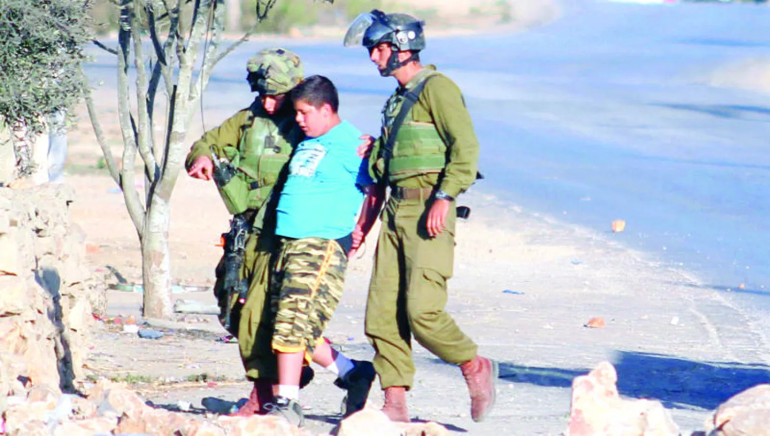 جنديان يعتقلان طفلا فلسطينيا خلال مشاركته في إحدى المظاهرات في الضفة الغربية (غيتي)