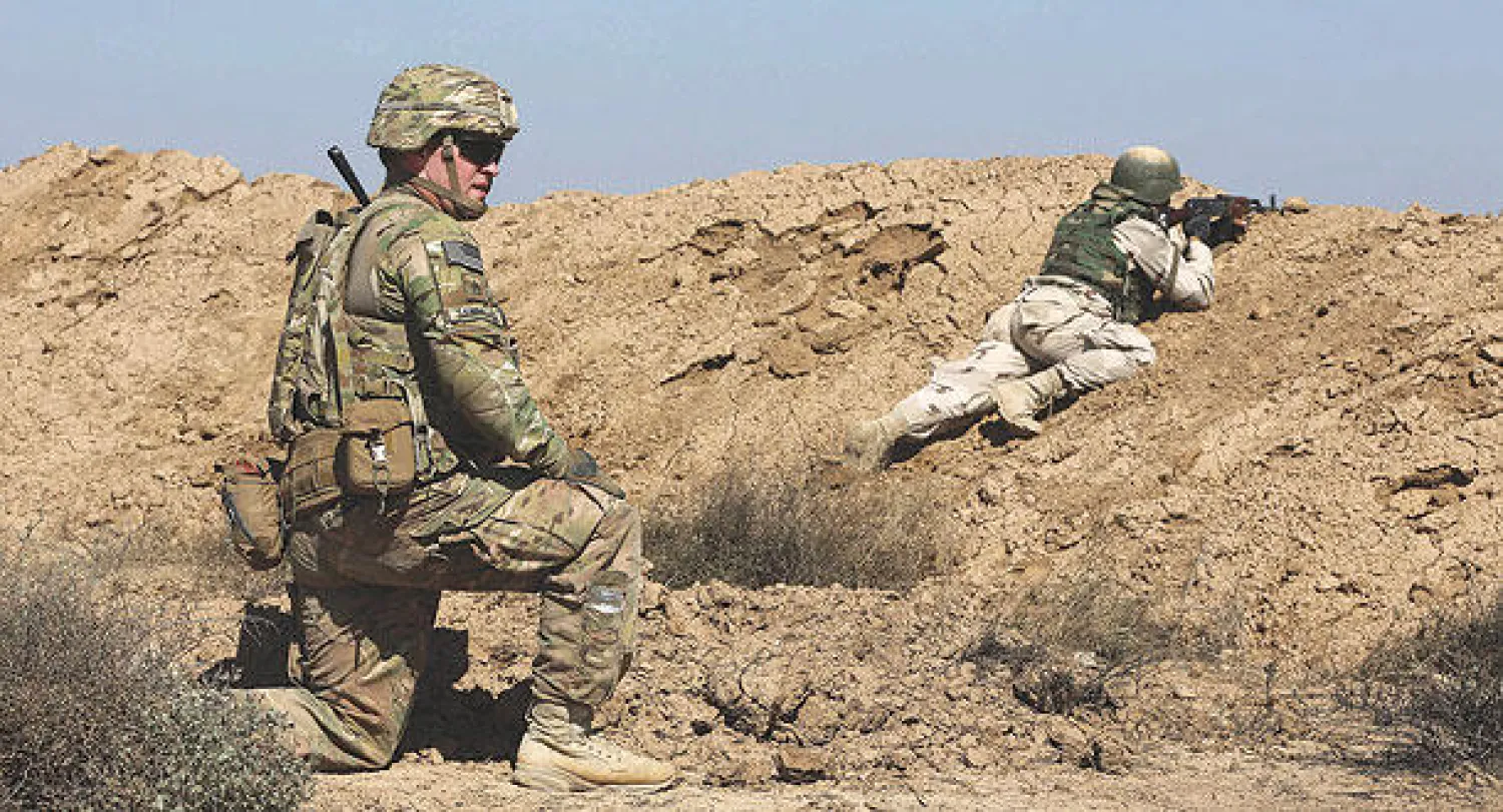 عسكري أميركي يدرب جنديًا عراقيًا على الرماية في معسكر التاجي شمال بغداد (أ.ب)