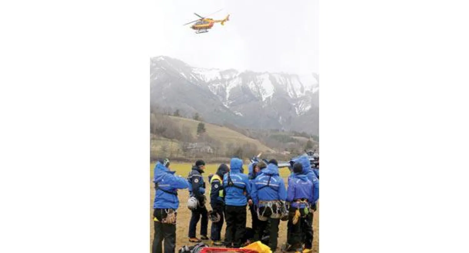 طائرة هليكوبتر تحلق بحثًا عن الطائرة المنكوبة بينما تبدو عناصر من الشرطة والدرك في مدينة سين لي ألب الفرنسية أمس (رويترز)