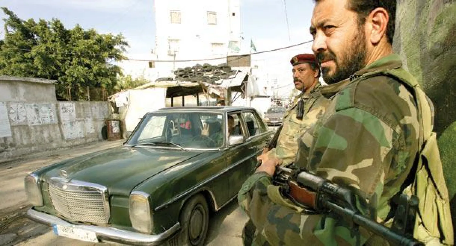 عنصران من الكفاح المسلح الفلسطيني أمام نقطة تفتيش في مخيم عين الحلوة بصيدا أمس (أ.ف.ب)