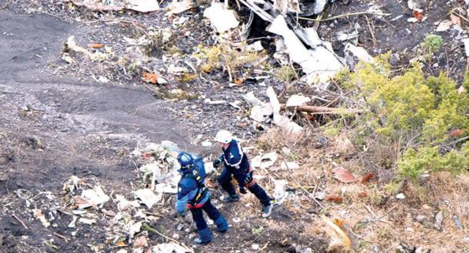 عاملا إنقاذ قرب حطام الطائرة في قلب جبال الألب أمس (أ.ب)