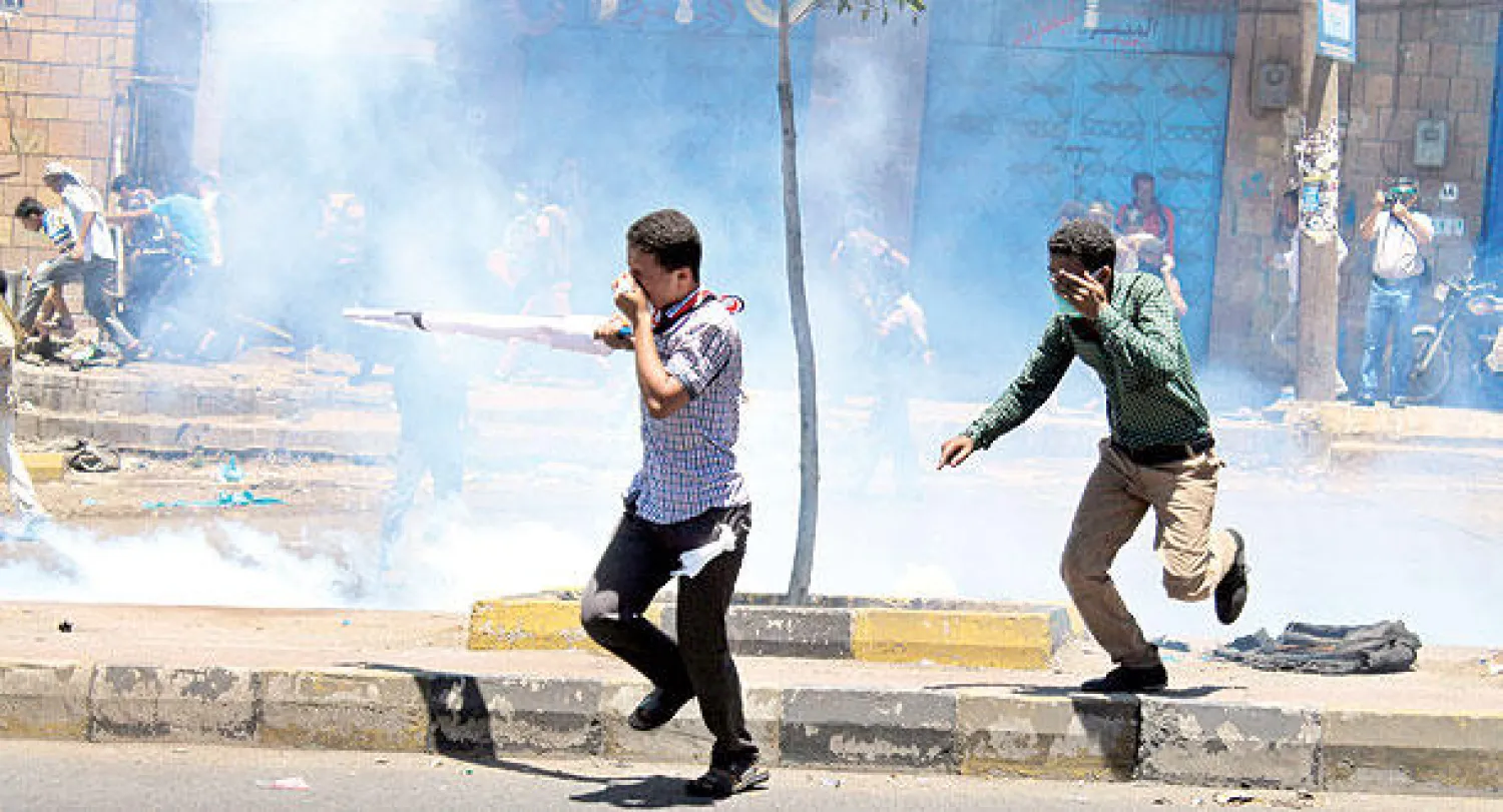 يمنيون يركضون هربًا من المقاتلين الحوثيين الذين أطلقوا قنابل الغاز أمس في تعز (إ.ب.أ)