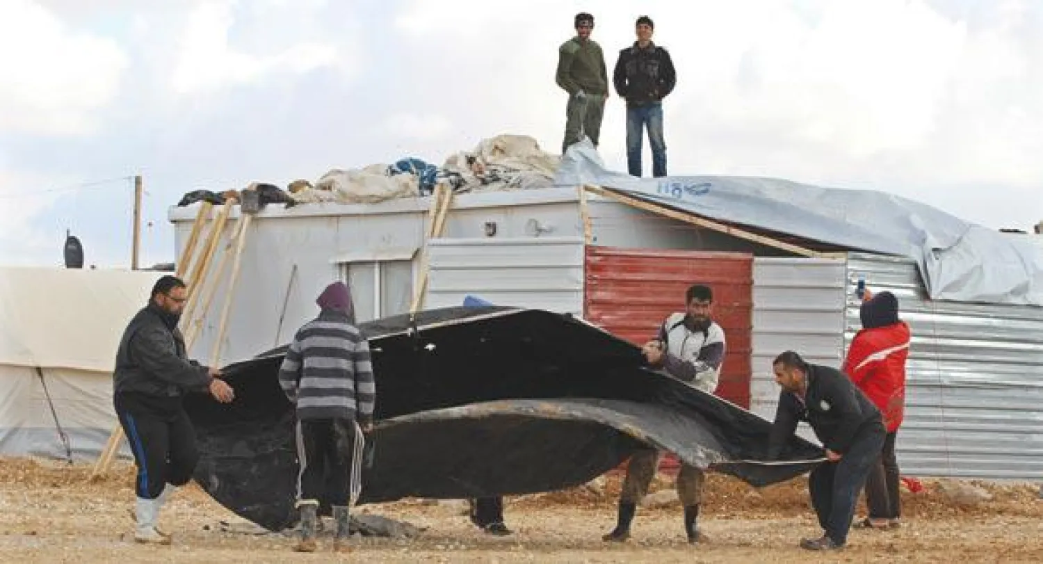 لاجئون سوريون في مخيم الزعتري يحاولون إعادة خيمة إلى وضعها الطبيعي بعد عاصفة (أ.ب)