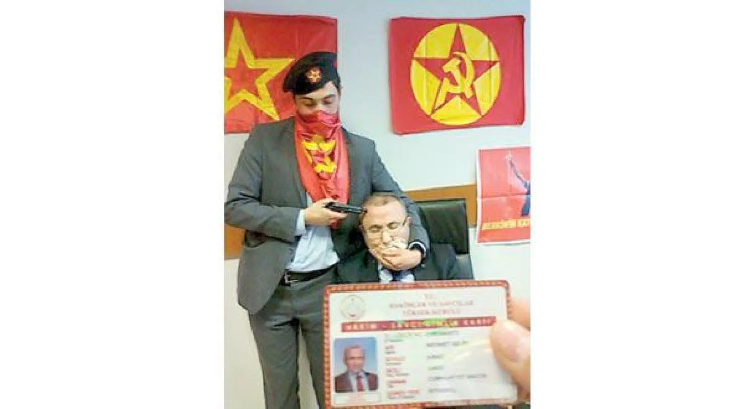 خاطف يصوب مسدسه إلى رأس المدعي العام محمد سليم كيراز وآخر يعرض بطاقته الشخصية بعد أن احتجزاه بمحكمة في إسطنبول اقتحماها مع مسلح ثالث أمس (رويترز)