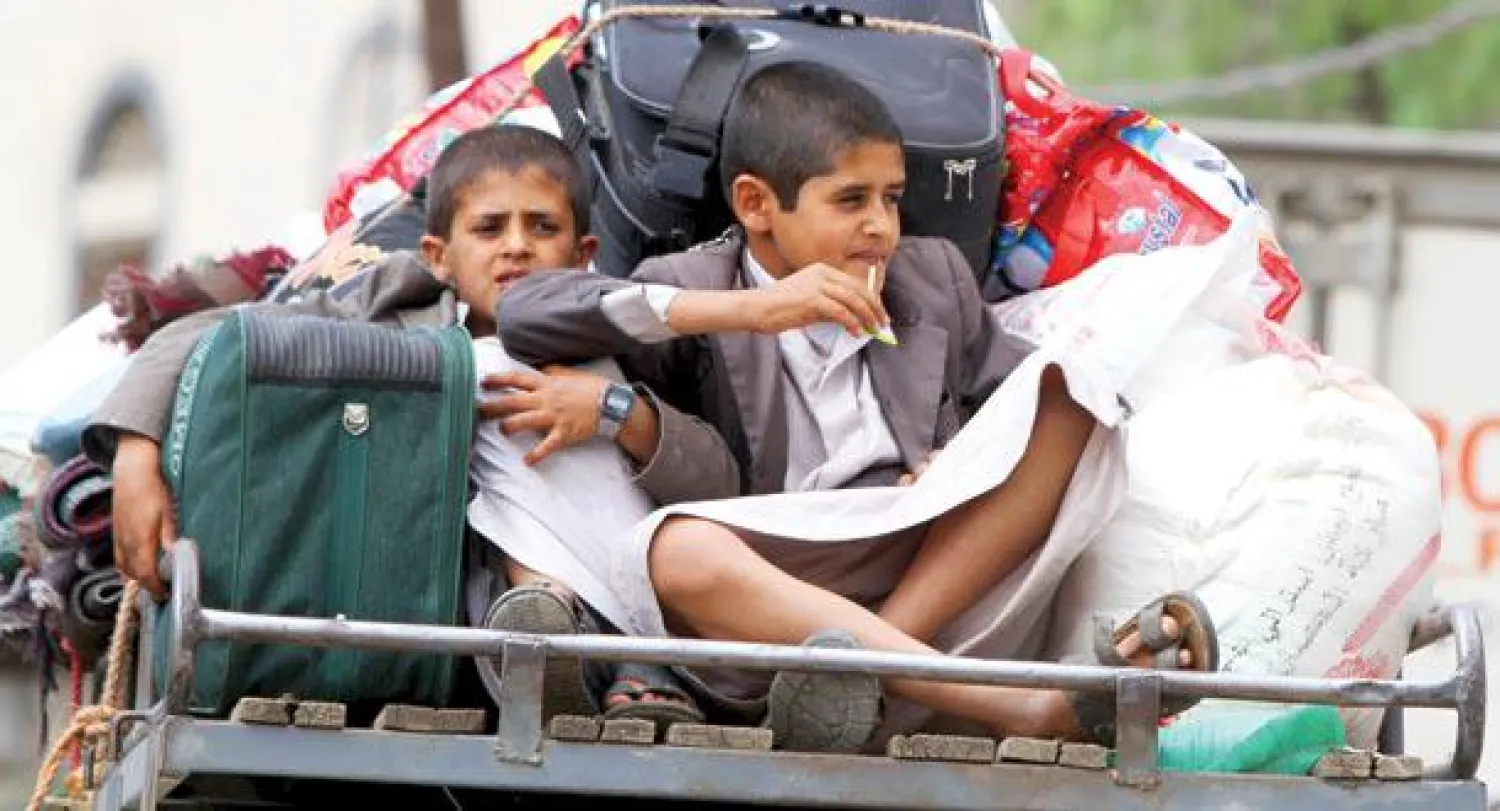 طفلان يجلسان في عربة نقل أثناء مغادرة عائلتهما لصنعاء في ضل حالة عدم الاستقرار فيها أمس (رويترز)
