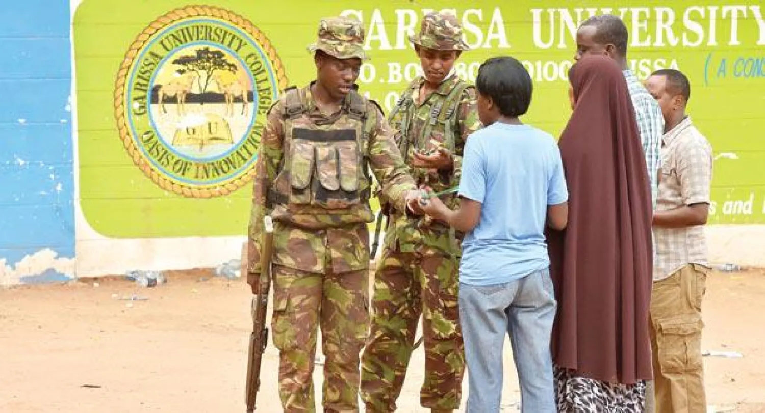 جنديان وعوائل الضحايا خارج جامعة موي في بلدة غاريسا في شمال شرقي كينيا عقب هجوم حركة الشباب الذي أودى بحياة 147 شخصًا أول من أمس (أ.ف.ب)