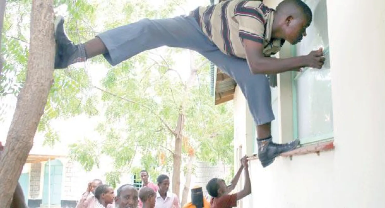 رجل ينظر أمس عبر نافذة إلى مشرحة يعتقد أن فيها جثث بعض منفذي الهجوم على الجامعة في مدينة غاريسا الكينية (رويترز)