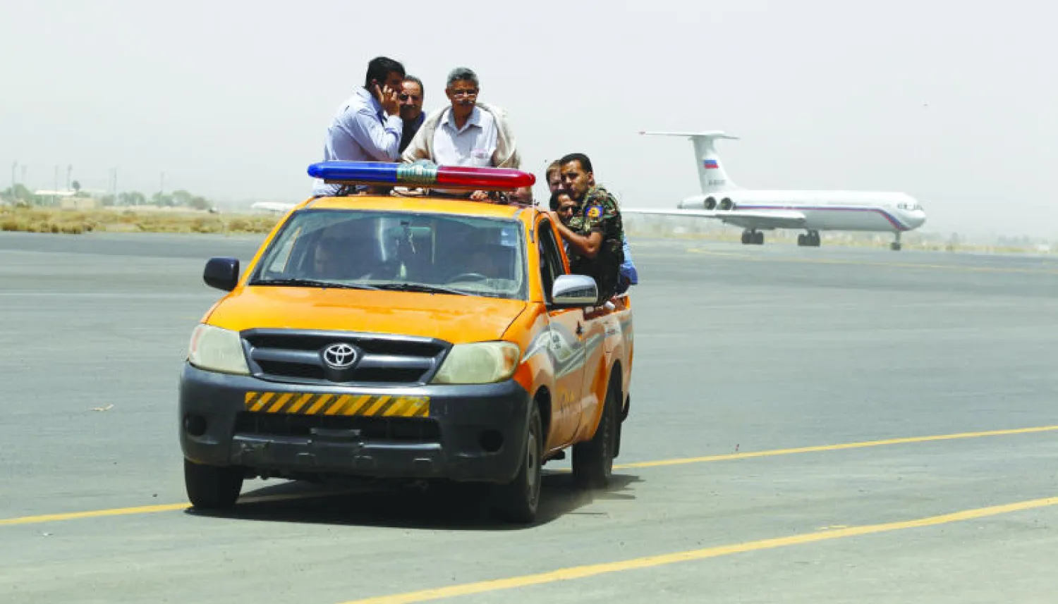 موظفون ورجال أمن في مطار صنعاء الدولي وتبدو طائرة روسية لإجلاء رعايا أجانب من اليمن أمس (إ.ب.أ)