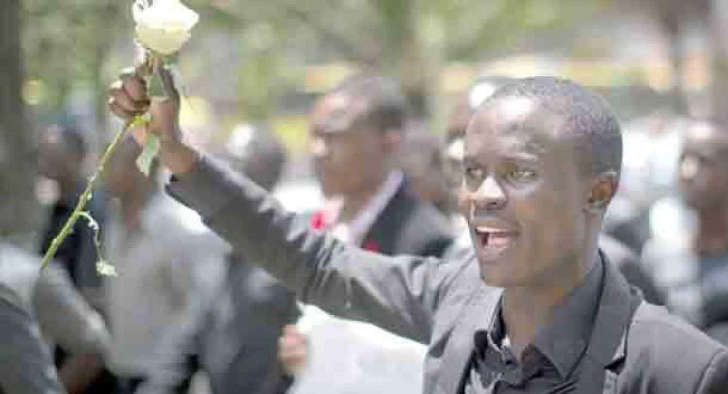 طالب يحمل وردة ويرتدي بدلة سوداء حدادا على ضحايا الهجوم على جامعة غاريسا خلال مظاهرة في نيروبي أمس (أ.ب)