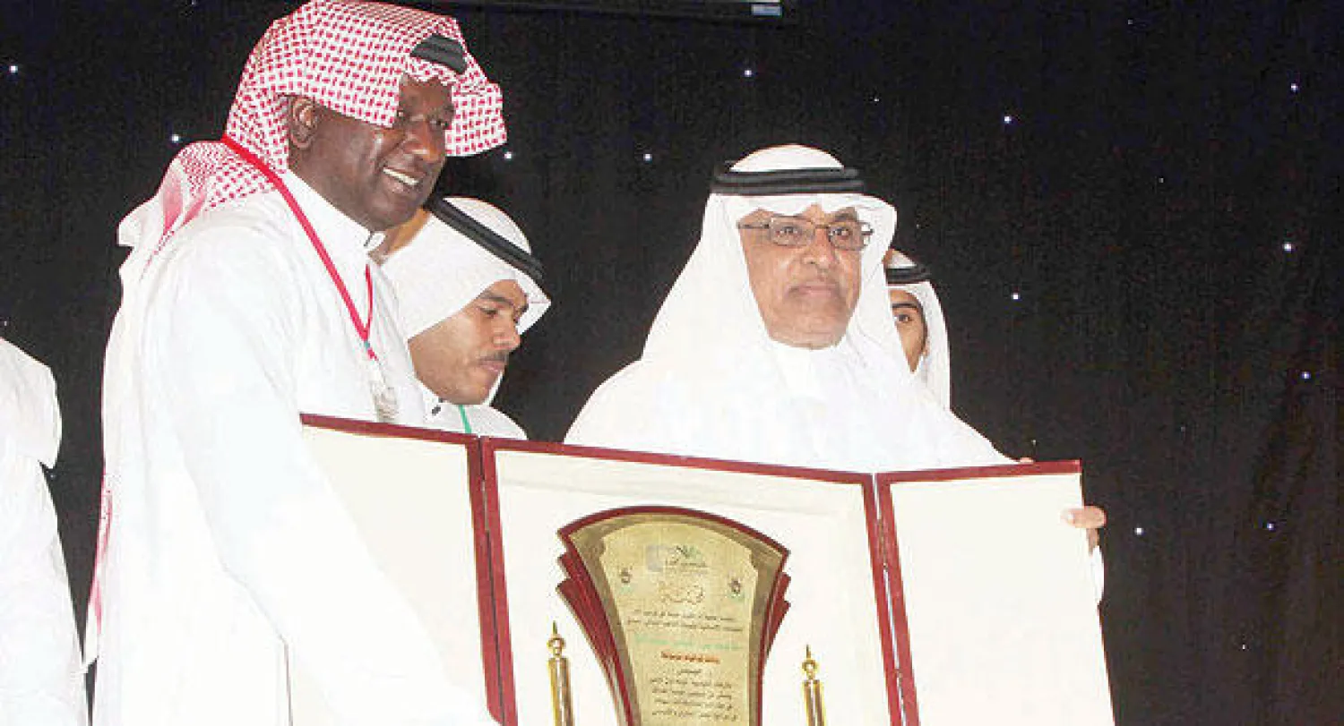 ماجد يتسلم درعا تذكارية من مدير جامعة أم القرى الدكتور بكري عساس (تصوير: أحمد حشاد)