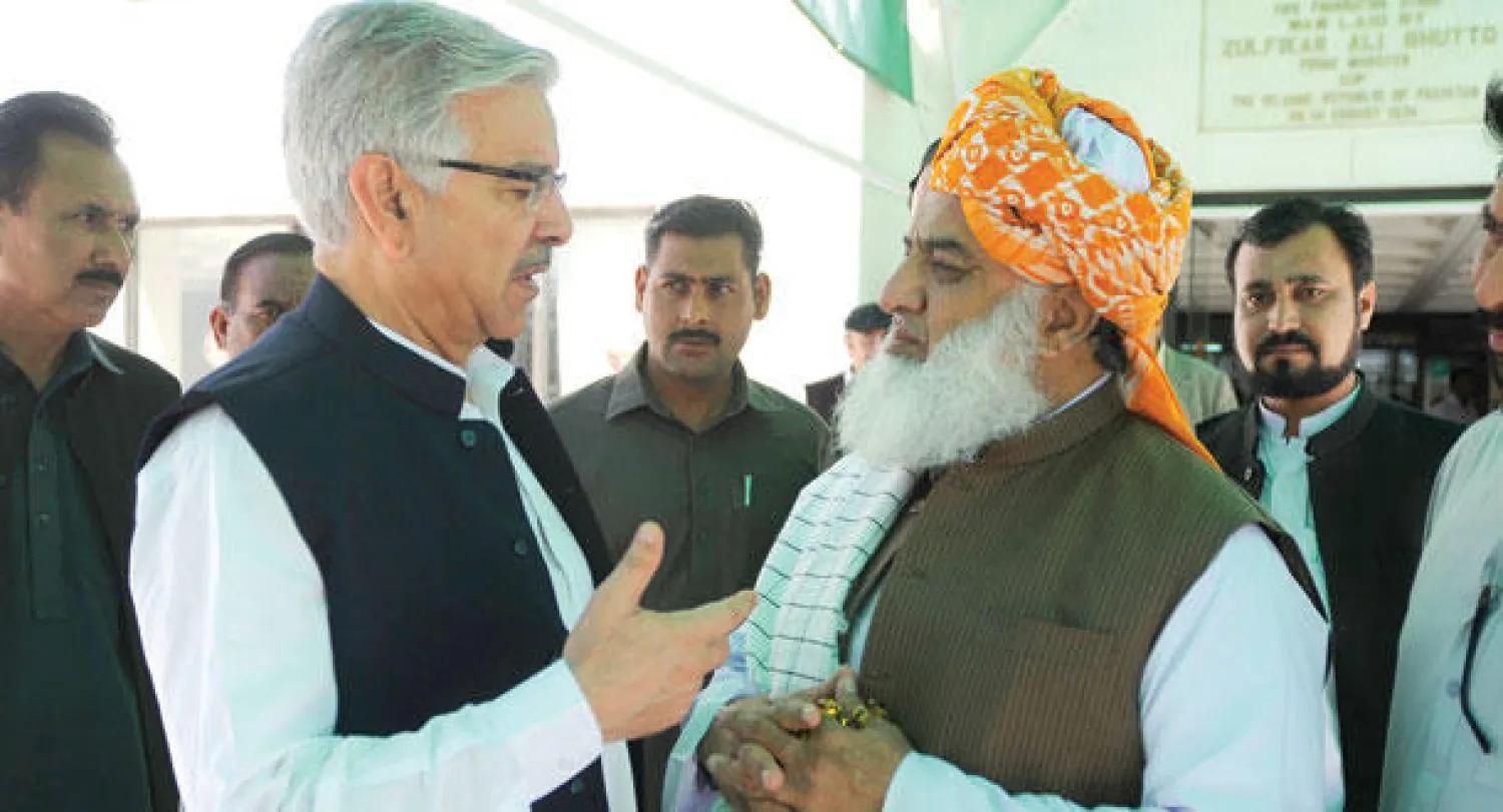 وزير الدفاع الباكستاني يتحدث مع مولانا فضل الرحمن زعيم حزب «جماعة علماء الإسلام»  خارج مقر البرلمان الباكستاني أمس (أ.ب)