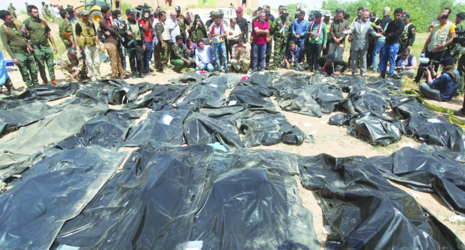 عراقيون يتجمعون حول أكياس تحوي رفات يعتقد أنها لمجندين أعدمهم «داعش» أخرجت من مقابر جماعية في تكريت أول من أمس (أ.ف.ب)