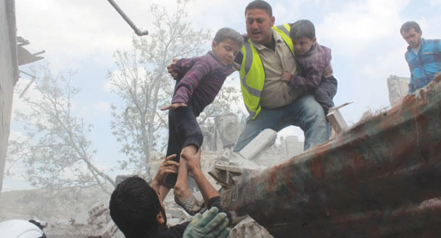 قوات الدفاع المدني في حلب تجلي الأطفال من مبنى تعرض لغارة جوية من طيران النظام (أ.ف.ب)