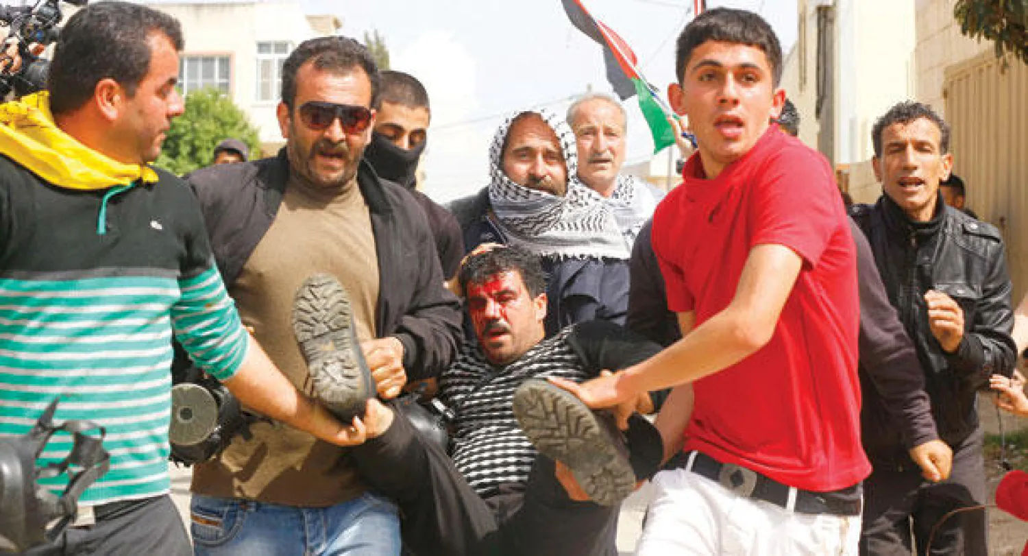 فلسطينيون يحملون شابا أصيب خلال مواجهات مع جنود إسرائيليين في مدينة نابلس أمس (إ.ب.أ)