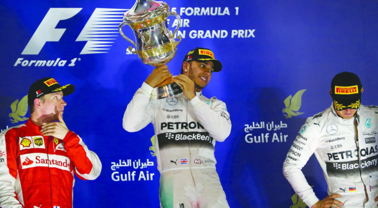 هاميلتون يحتفل بكأس سباق البحرين على المنصة بين روزبرغ ورايكونن (أ.ف.ب)