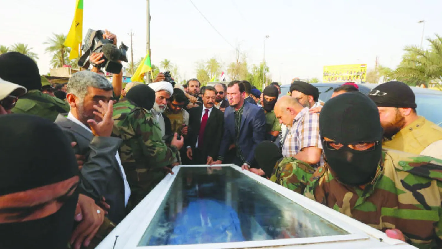 عناصر في «كتائب حزب الله» ومدنيون يحملون نعشا بداخله جثة يعتقد أنها لعزة الدوري تمهيدا لتسليمها لوزارة الصحة العراقية أمس (أ.ب)