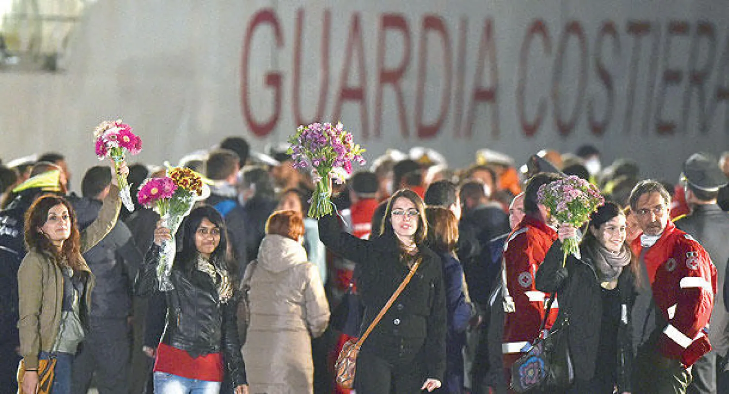 ناشطون يحملون باقات من الزهور لدى استقبال مهاجرين أنقذتهم سفن خفر السواحل الإيطالية مساء أول من أمس (أ.ب)