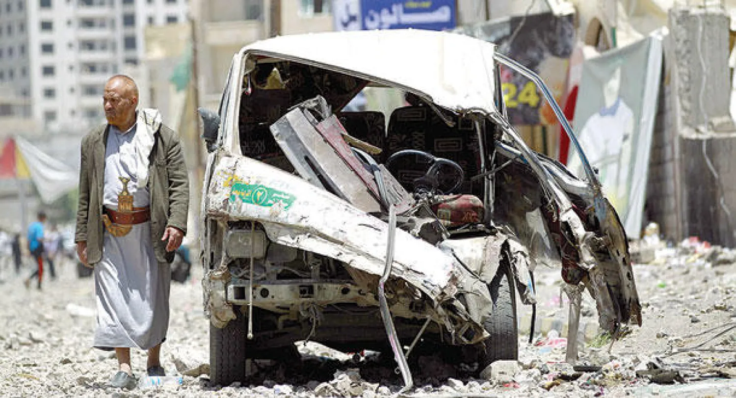 يمني يسير بمحاذاة مركبة معطوبة قرب قاعدة فج عطان القريبة من صنعاء أمس (أ.ف.ب)