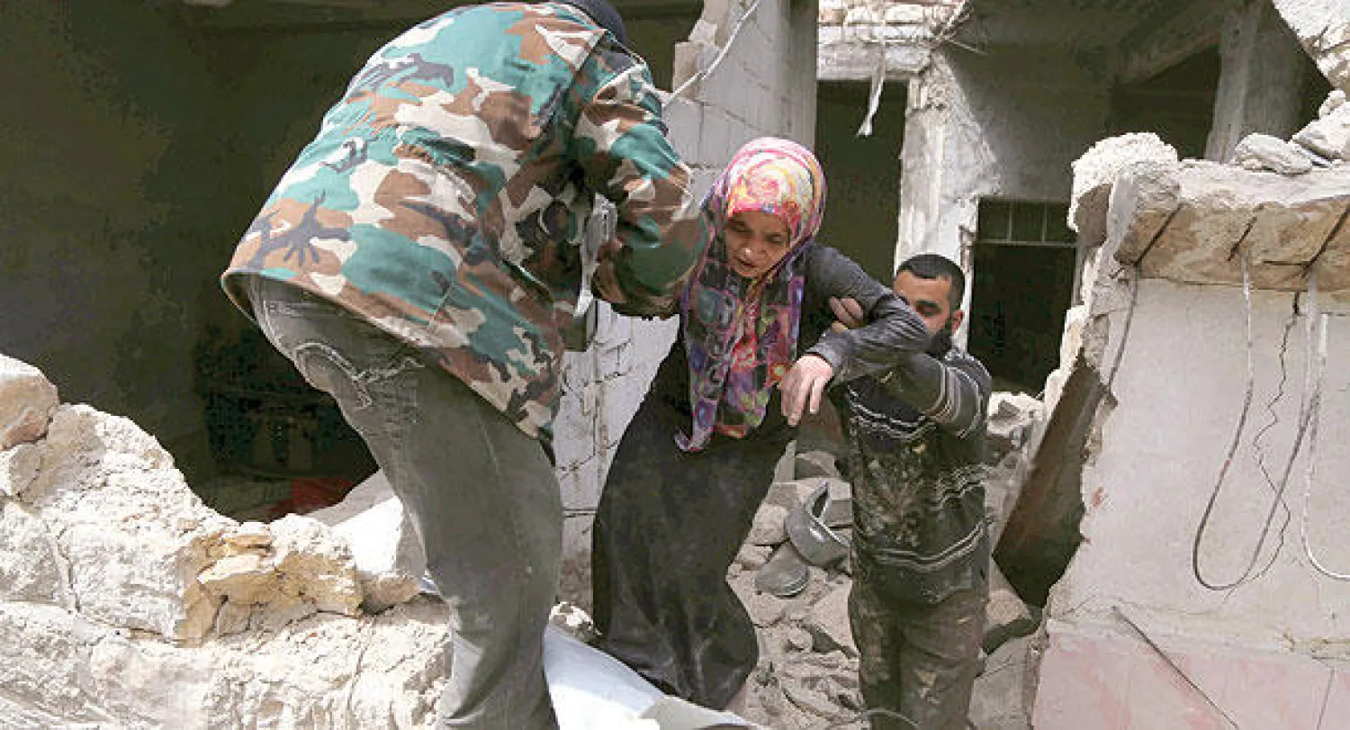 سكان حي الصاخور في حلب يساعدون امرأة على الخروج من بين ركام منزلها بعد وفاة عائلتها إثر غارة من طيران النظام (رويترز)