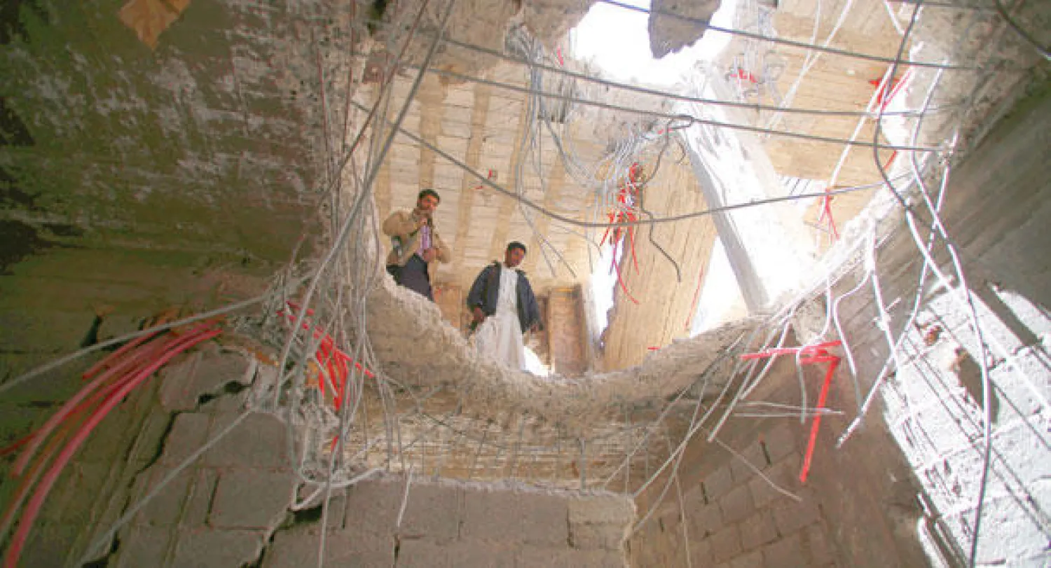 مقاتلان يمنيان يتطلعان من ثغرة أحدثها قصف التحالف في مخزن أسلحة تابع للمتمردين الحوثيين في صنعاء أمس (أ.ب)