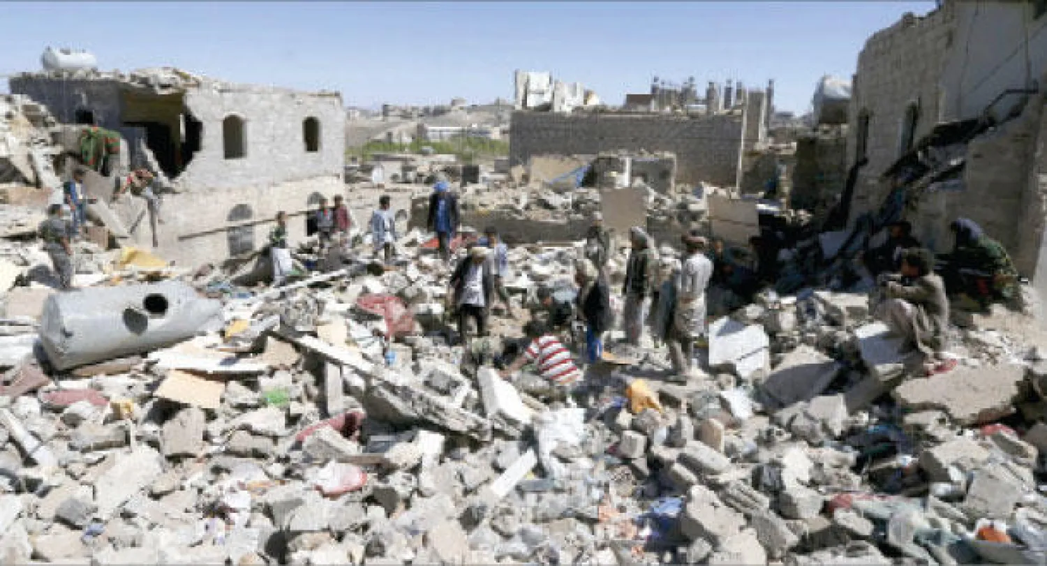 يمنيون يقفون على مواقع  للمتمردين الحوثيين استهدفها طيران التحالف في صنعاء أمس (رويترز)