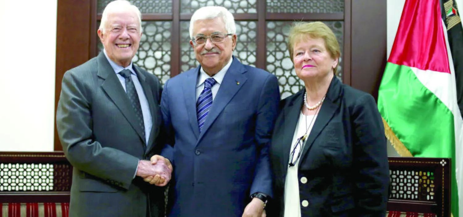 الرئيس الأميركي الأسبق جيمي كارتر يصافح الرئيس عباس وتقف إلى جانبهما رئيسة وزراء النرويج السابقة جرو هارلم برونتلاند خلال اللقاء الثلاثي الذي أقيم بمقر عباس في رام الله أمس (رويترز)