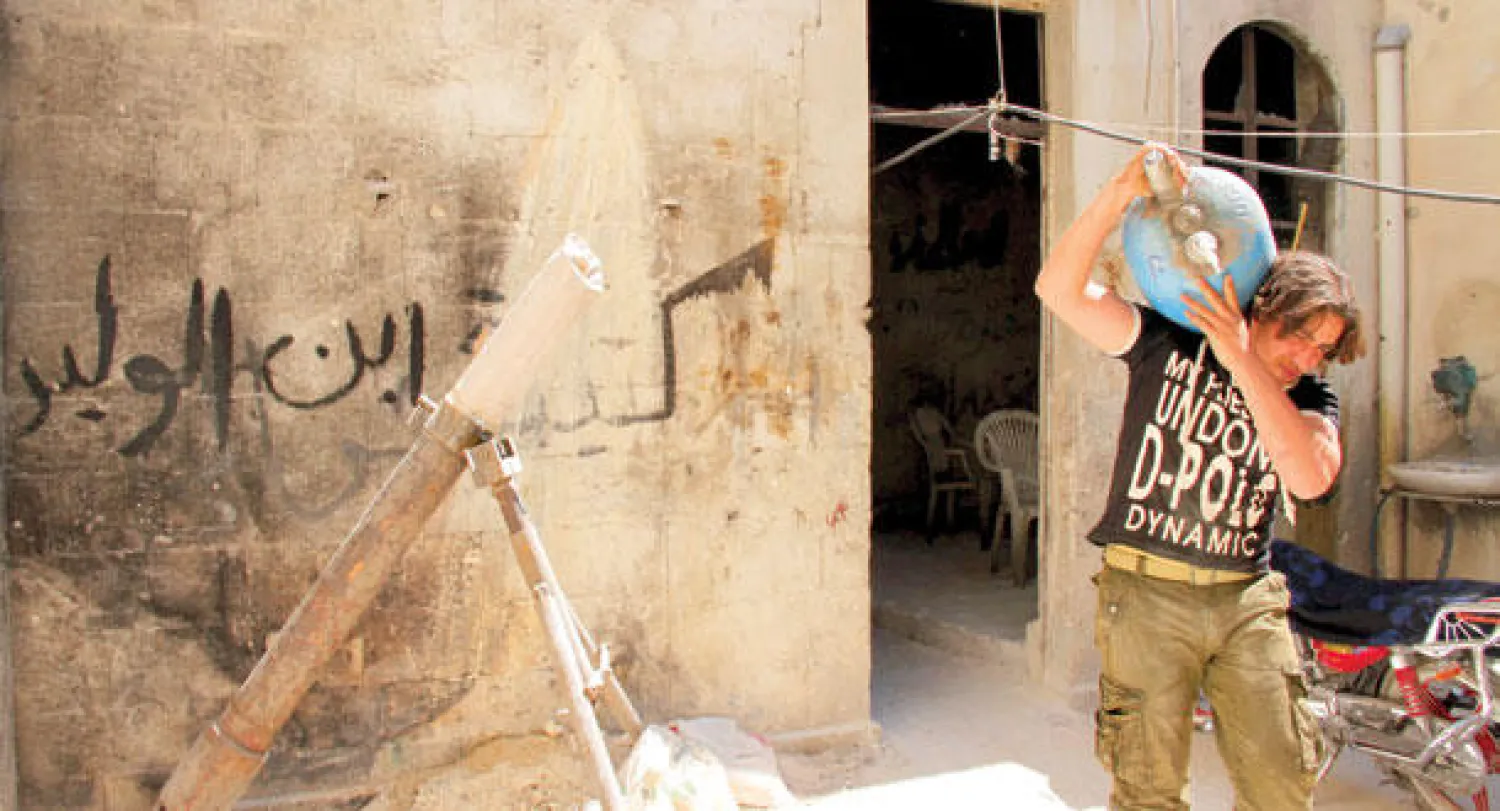 مقاتل من أفراد «الجيش السوري الحر» يحمل قذيفة مصنوعة محليا قبل استخدامها في القصف على مواقع قوات نظام الأسد في محلة الجديدة أحد أحياء حلب القديمة (رويترز)