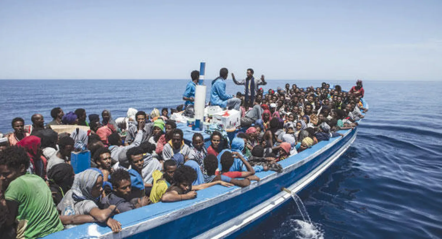 مهاجرون في قارب مصنوع من الخشب يقتربون من الساحل الإيطالي في البحر الأبيض المتوسط (أ.ف.ب)