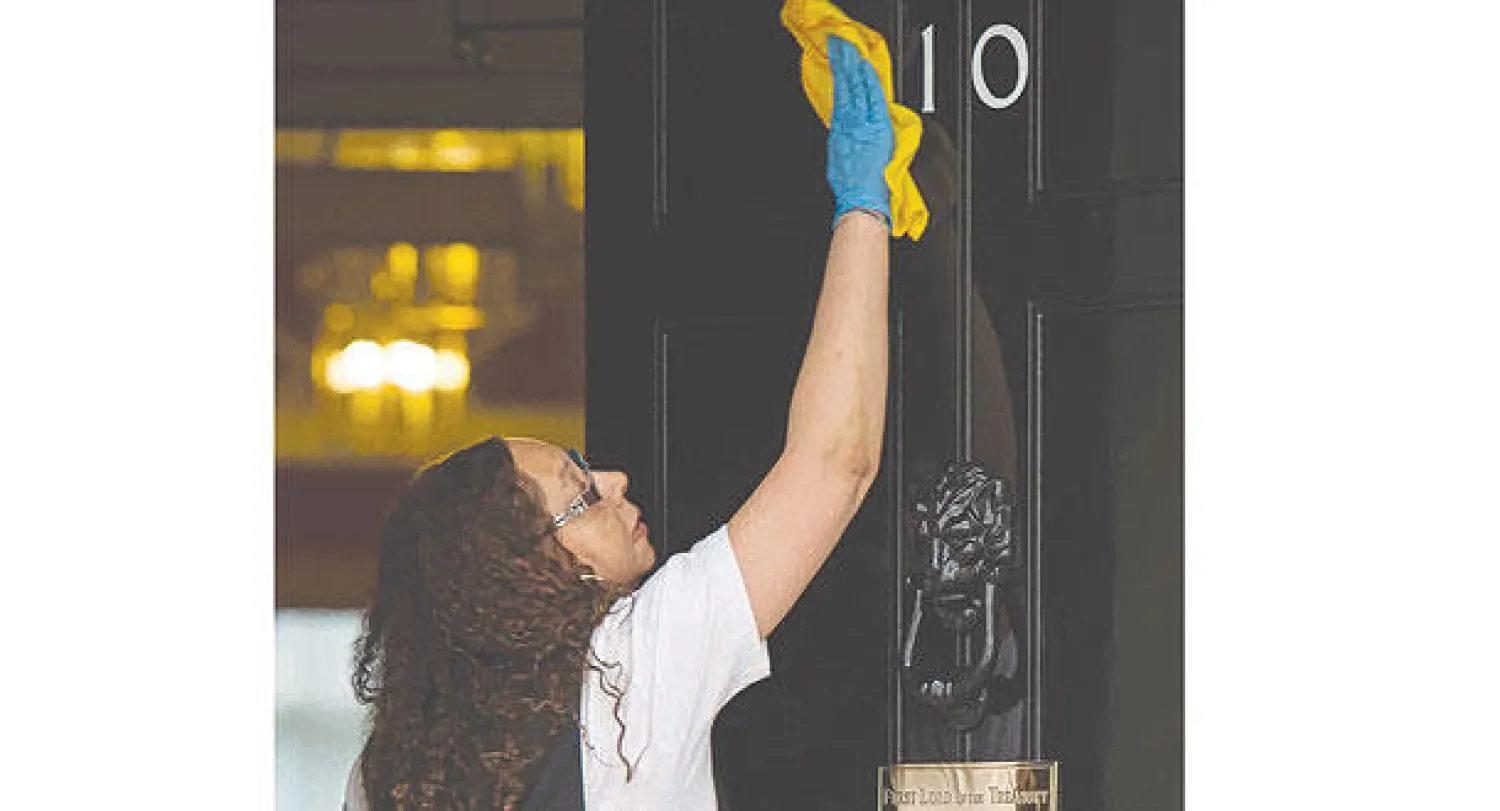 امرأة تنظف باب مبنى 10 داوننغ ستريت (مقر رئاسة الوزراء) في لندن أمس (أ.ف.ب)