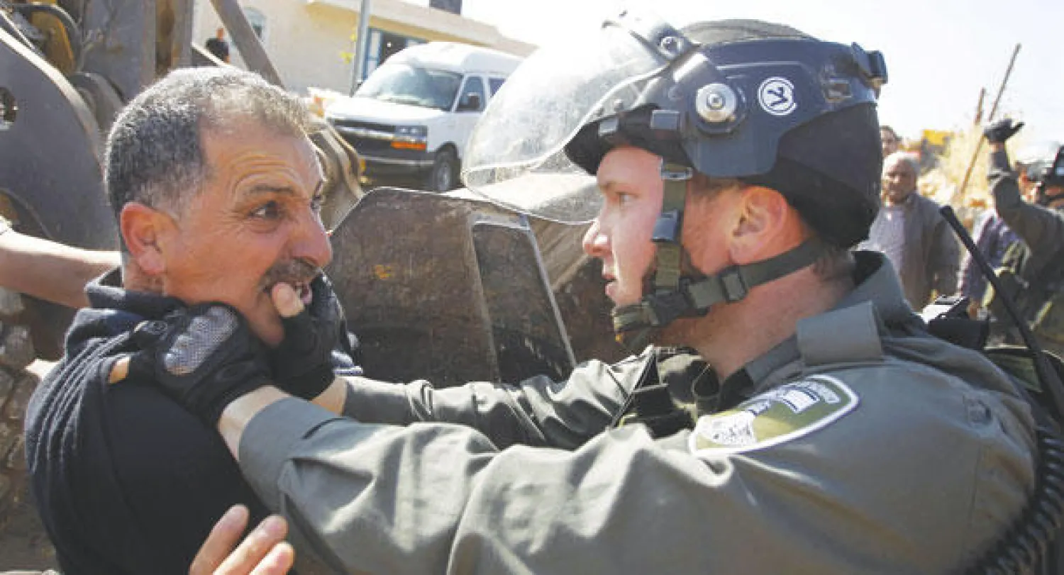 فلسطيني يواجه شرطيا إسرائيليا بينما يهد جيش الاحتلال منزله بقرية سوسيا جنوب الخليل (إ.ب.أ)