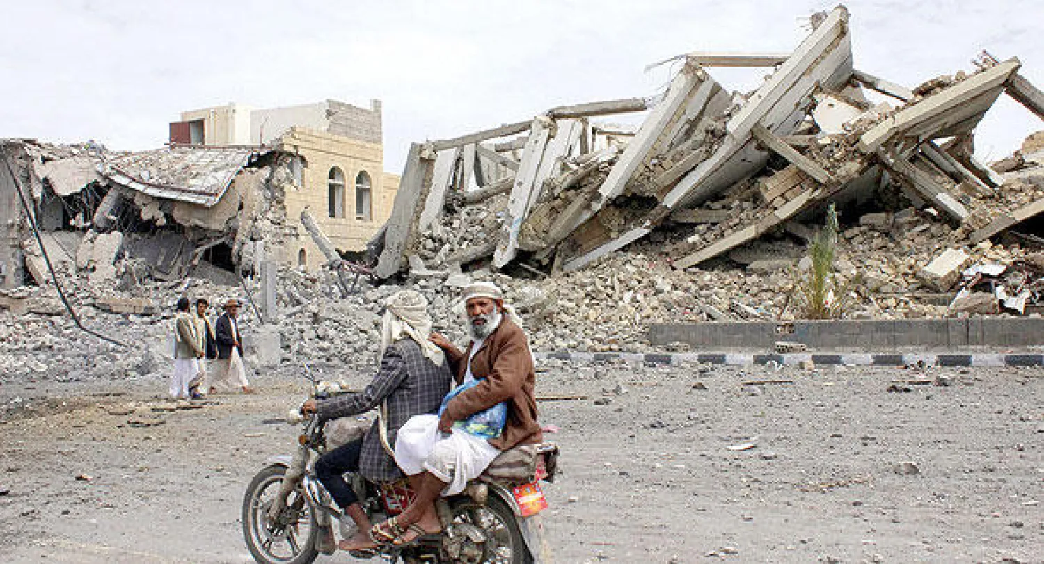 يمنيان على دراجة نارية أمام مبنى مركز للشرطة قصفته قوات التحالف بعد استحواذ الحوثيين عليه في صعدة أمس (رويترز)