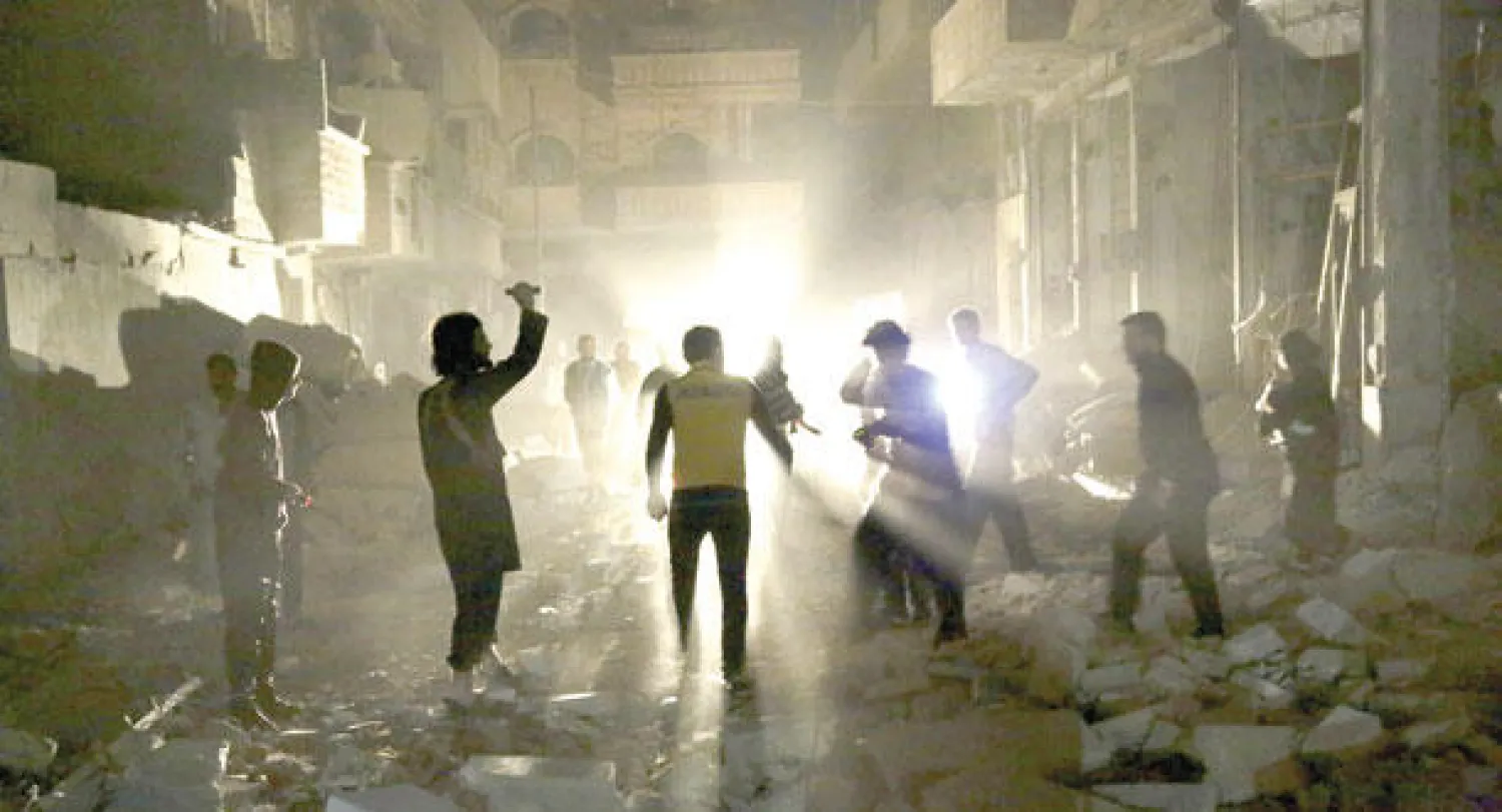 سوريون يتفقدون ركام بيوتهم التي دمرتها البراميل المتفجرة في مدينة معرة النعمان بجنوب محافظة إدلب (رويترز)