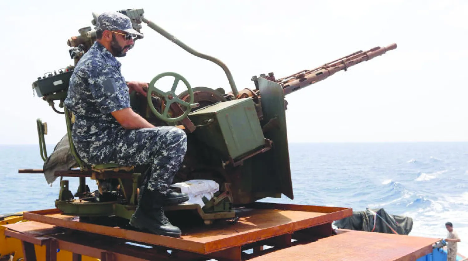 عنصر من خفر السواحل الليبي يراقب ساحل مدينة مصراتة شرق البلاد أول من أمس (أ.ف.ب)