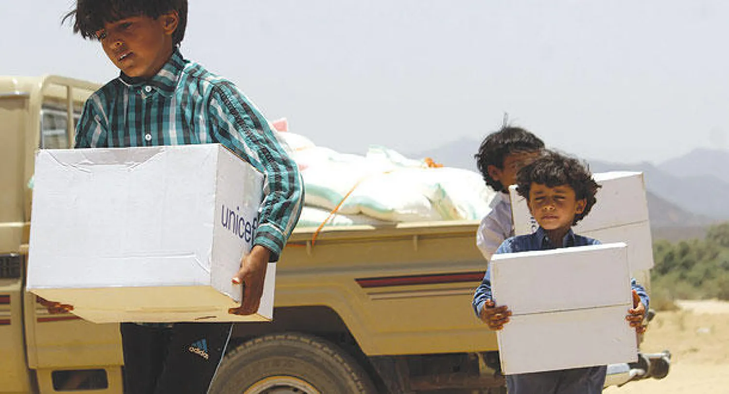 ثلة من الأطفال اليمنيين النازحين الذين فروا مع عائلاتهم يحملون صناديق المساعدات الإنسانية  التي تبرعت بها اليونيسيف في محافظة مأرب، شرق العاصمة صنعاء (أ.ف.ب)