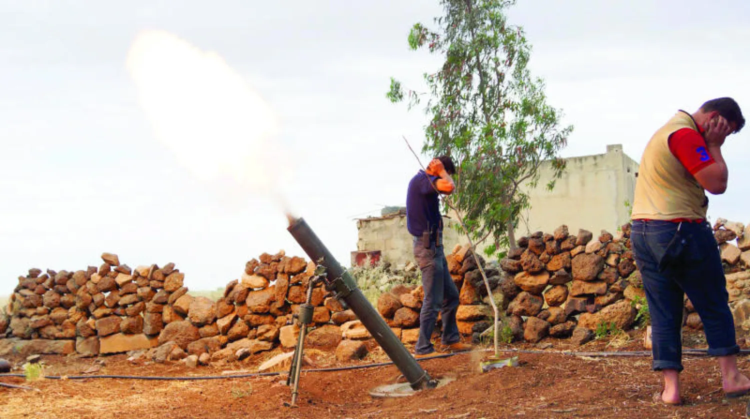 مقاتلان من الجيش السوري الحر يحميان آذانهما من صوت إطلاق قذيفة مورتر على قوات الأسد ومواليه في ريف درعا (رويترز)
