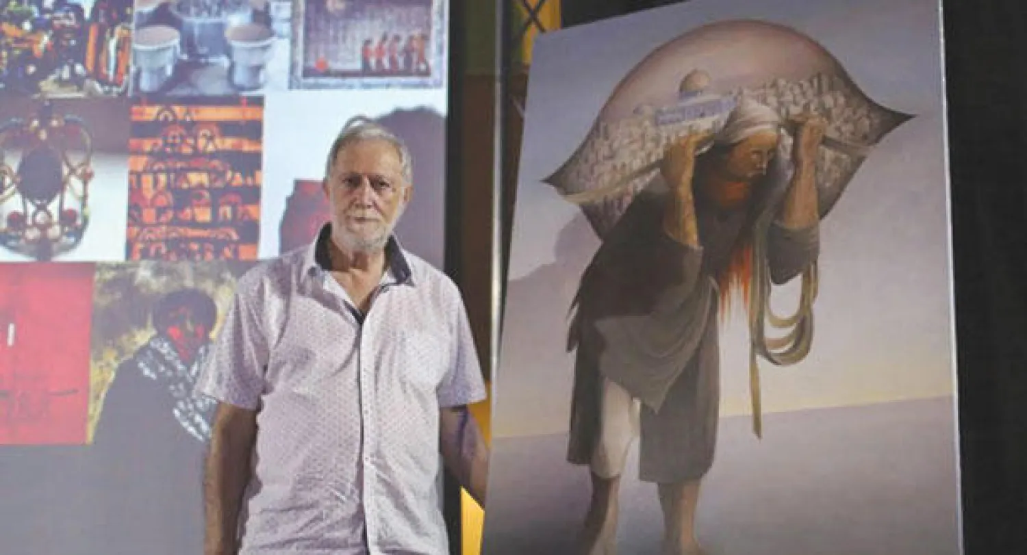 التشكيلي الفلسطيني سليمان منصور إلى جانب لوحته الشهيرة «جمل المحامل»