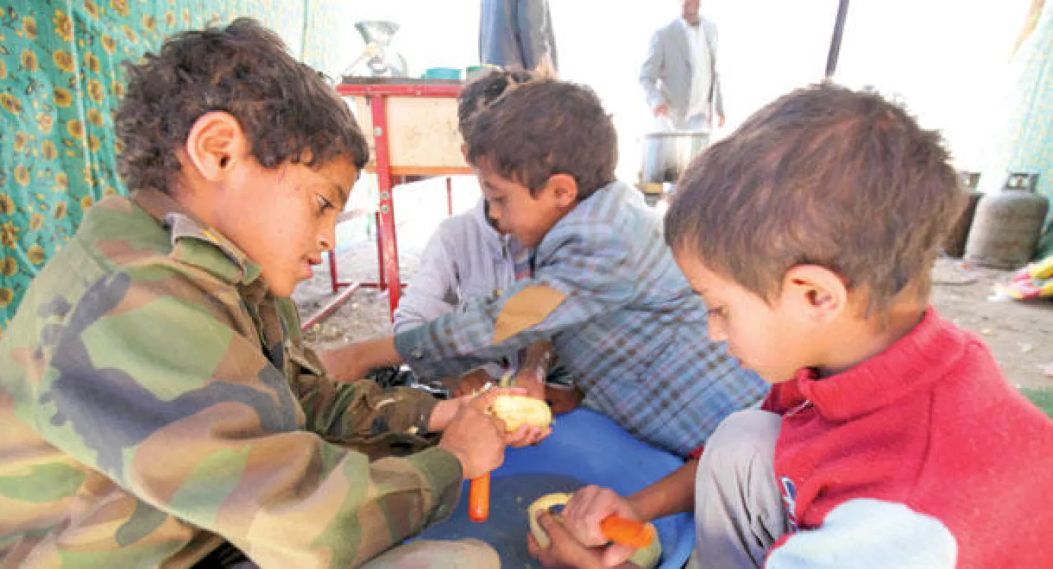 أطفال يمنيون نازحون يعدون الطعام في مدرسة بصنعاء (رويترز)