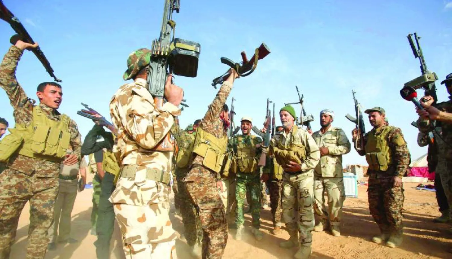 عناصر في الحشد الشعبي يرددون هتافات تحد في ناحية النخيب المتاخمة لكربلاء في محافظة الأنبار أمس (أ.ف.ب)