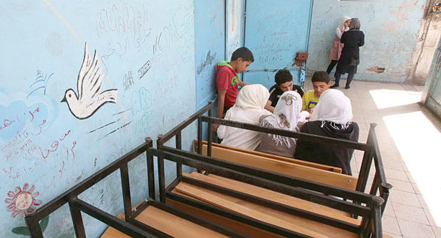 فلسطينيون لاجئون من مخيم اليرموك في دمشق يراجعون مقرراتهم الدراسية قبل الدخول إلى الفصول  لتقديم امتحاناتهم النهائية لهذا العام بمدارس الأونروا (أ.ف.ب)